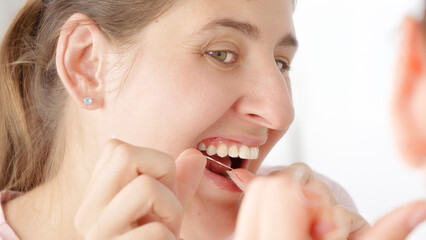 Young woman using dental floss to clean stuck food out of her teeth. Concept of teeth health, self...