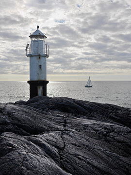 Lighthouse and rocks on coast at sunset