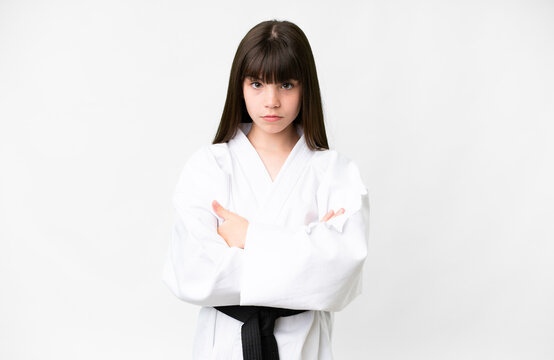Little caucasian girl over isolated white background doing karate keeping the arms crossed