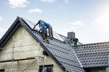 Workers installing solar panels on the roof of a German single family home