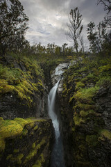 Fototapeta na wymiar Waterfall in canyon under clouds