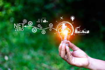 Net zero concept. Hand holding bulb with net zero icon. It is surrounded by a clean energy icon. Net zero 2050. Carbon gas affects global warming. Concept with innovation inspiration from big data. - obrazy, fototapety, plakaty