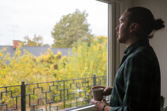 Young man with cup of coffee by window