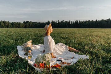 Woman in hat rear view, picnic in field.
