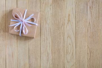 Gift box with bow on wooden background with copy space