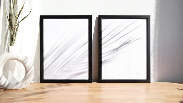 Video of two black photo frames with white round vase on wooden table