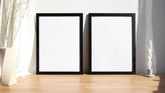 Video of two black photo frames with beige vase on wooden table