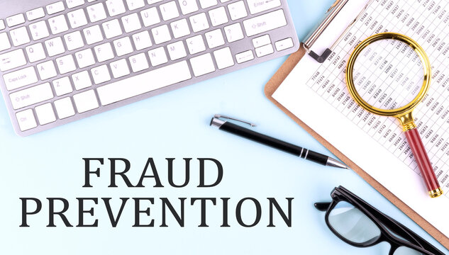FRAUD PREVENTION text on blue background with keyboard and clipboard, business concept
