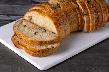 Bread with olives on a white cutting board on a gray table