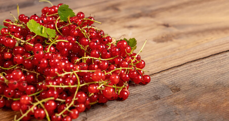 Fresh red currants with leaves on a brown wooden table on background. Harvest of ripe summer berries. Closeup.