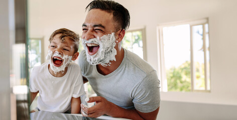 Fun on father's day: Dad and his son have fun shaving together - obrazy, fototapety, plakaty