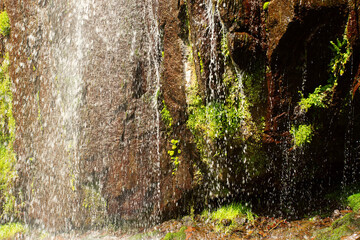 Refreshing waterfall with a natural pool for swimming, water stream falls from above from a rock onto stones