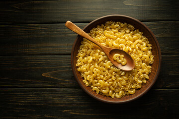 A plate of raw pasta and a spoon on a vintage table before cooking. Place for recipe or menu on...