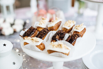 Homemade eclairs or profiteroles with custard and chocolate. Traditional french eclairs, dessert. Candy bar. Dessert table for party goodies. Party reception, decorated delicious in the restaurant.