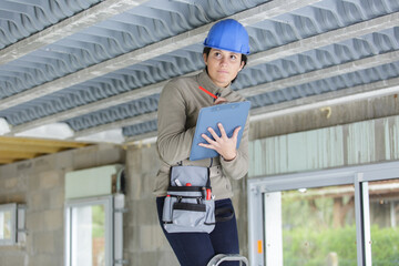 woman on stepladder writing on clipboard