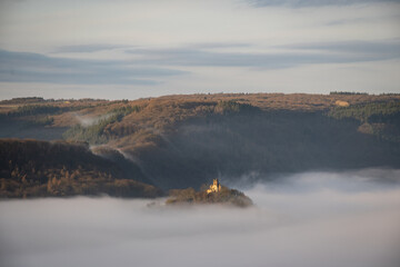Remains of ruin Wolf Monastery or Ruine der Liebfrauenkirche in mosselle valley wine region in Germany above morning mist fog just after sunrise. dreamy fairy tale effect with natural beauty
