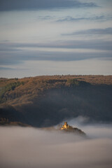 Remains of ruin Wolf Monastery or Ruine der Liebfrauenkirche in mosselle valley wine region in Germany above morning mist fog just after sunrise. dreamy fairy tale effect with natural beauty
