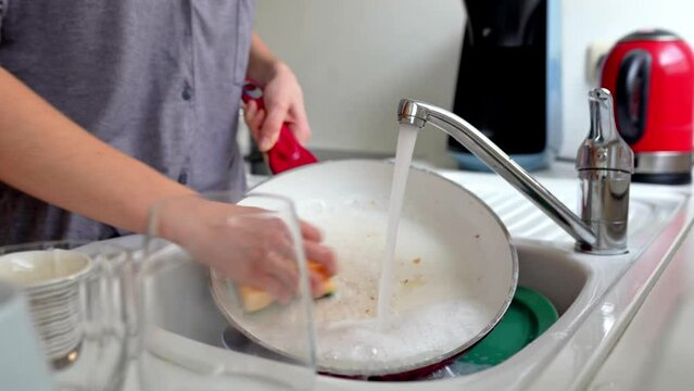 Washing dirty dishes in kitchen sink after dinner