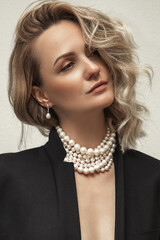 Beautiful young blondy woman with a lot of jewelry around her neck. Lots of pearl necklaces and...