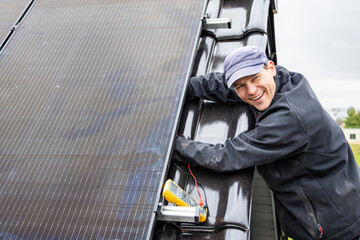Smiling technician working on the installation of a solar panel on a roof