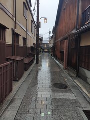 Fototapeta na wymiar L'insolite et touristique quartier de Gion, avec des petites ruelles à l'asiatique, de l'ancien Japon, sous un temps de pluie, avec ciel nuageux, des gens se promenant avec des parapluies