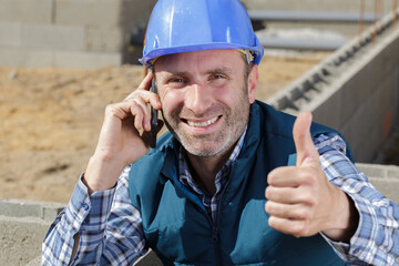 male builder on the telephone making thumbs-up gesture