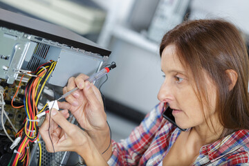 woman uses a screw driver to fix a pc