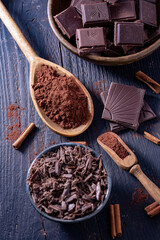 Pieces of chocolate, ground cocoa and beans put on a wooden plate