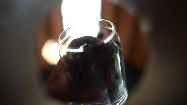 the barista's hand puts coffee beans into the container that covers the video recording