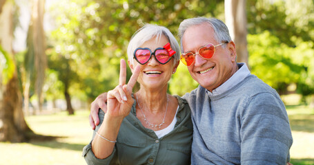 Funny couple, peace sign and portrait outdoor at a park with love, care and hand emoji. A happy senior man and woman with comic sunglasses in nature for happiness, healthy marriage and retirement fun