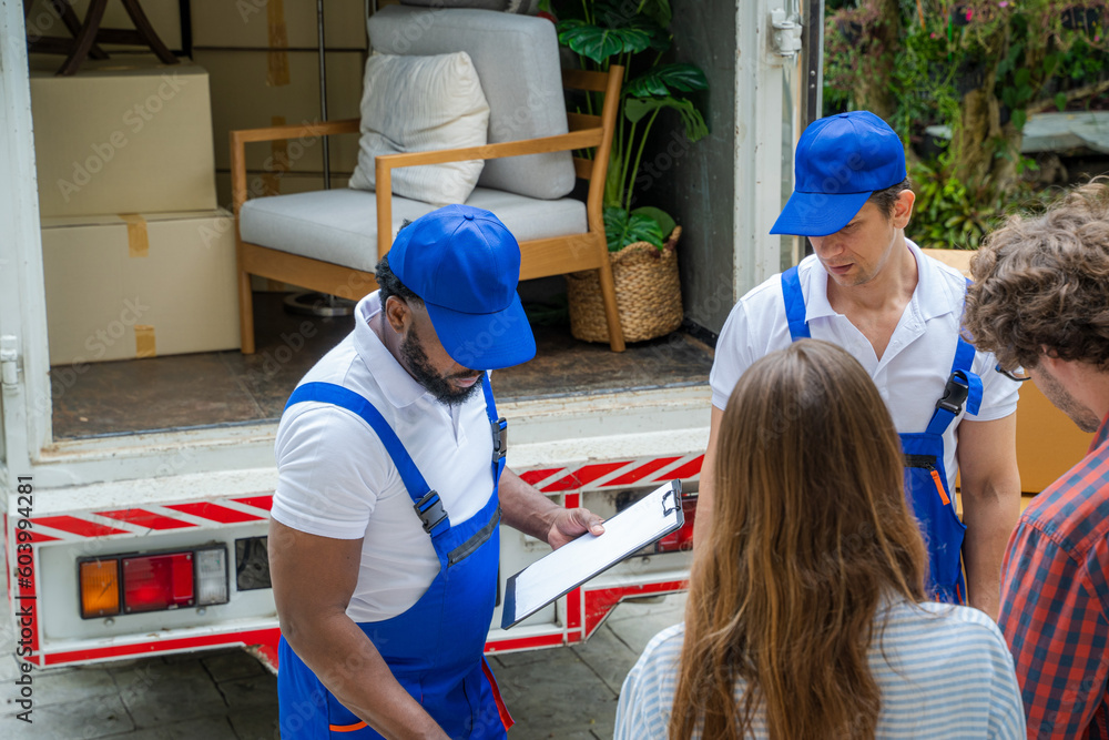 Poster happy couple with moving boxes at new house,moving company employee checks boxes in a truck before s