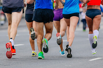Naklejka premium legs mixed group runners athletes running marathon in road, male and female joggers summer sports race