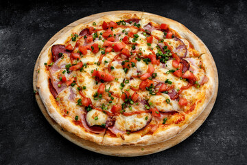 Pizza with cheese, smoked meat, tomatoes, sausage and ketchup, close-up