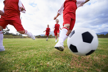 Running, teamwork and closeup with children and soccer ball on field for training, competition and fitness. Game, summer and action with football player and kick on pitch for goals, energy or athlete - obrazy, fototapety, plakaty