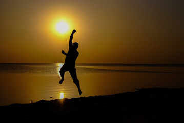 Trying to catch the sun by hand in a silhouette on the beach
