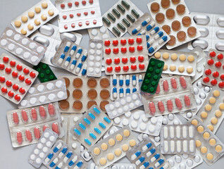 Health care concept. Checking medicine cabinet pills for expired medicines. Expiration date is indicated on packages of medicines. Pile of pills on gray table. Medicines background. Flat lay, close-up