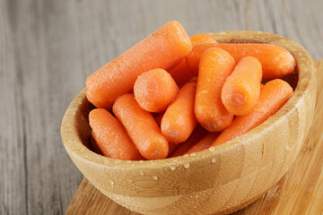 Close up of wooden bowl filled with delicious Baby Carrots