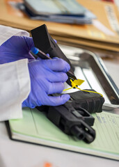 Police scientist writes serial number on firearm magazine in crime lab, conceptual image