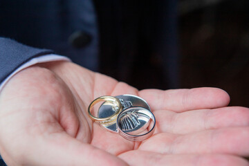 mans hand with 2 wedding rings & a wedding coin.