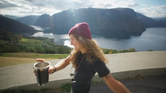Amazing wanderlust vibes travel couple bloggers walk out of side door of adventure camper van. Man pass coffee cup to woman, look at epic Norway views. Travel influencer lifestyle and camper roadtrip