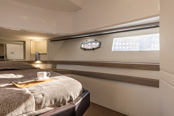 Interior of a luxury yacht bedroom with bed and coffee cup. Nobody inside - 604002215