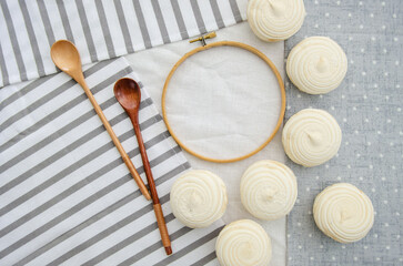Meringue homemade zephyr marshmallows with round embroidery hoop frame and wooden spoons on cotton tablecloth. Mockup card. Template for recipes, food menu, craft