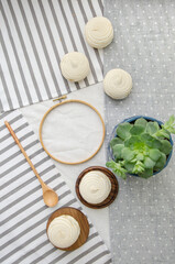 Meringue homemade zephyr marshmallows with round embroidery hoop frame, wooden spoon, echeveria plant on cotton tablecloth. Mockup card. Template for recipes, food menu, craft