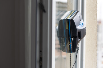 Crop of smart vacuum cleaner washing windows. Home appliance and technology concept