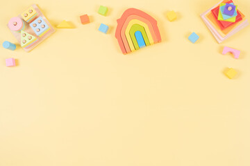 Baby kids toys banner background. Wooden educational, sensory, sorting and stacking toys on pastel yellow background. Top view, flat lay