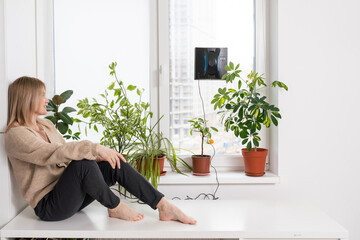 Woman cleaning windows at home with robotic cleaner.