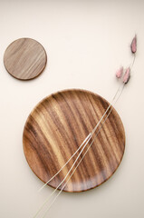 Decorative wooden plates on beige background with dried pink grass flowers. Natural organic products concept. Copy space, mock up. Spa background.