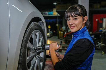 Fototapeta na wymiar Young female mechanic checking the air pressure of a car's tires.