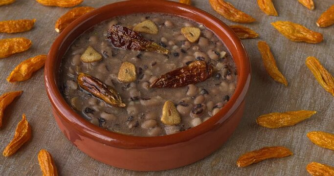 Vegan Frijoles refritos. Refried beans with fried garlic and chili on coconut oil. Dried chilies on the table.
