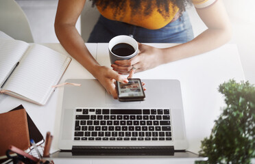 Coffee, top view of businesswoman with a cellphone and laptop by her desk in modern office. Networking or technology, communication and black woman with smartphone on social media at workplace